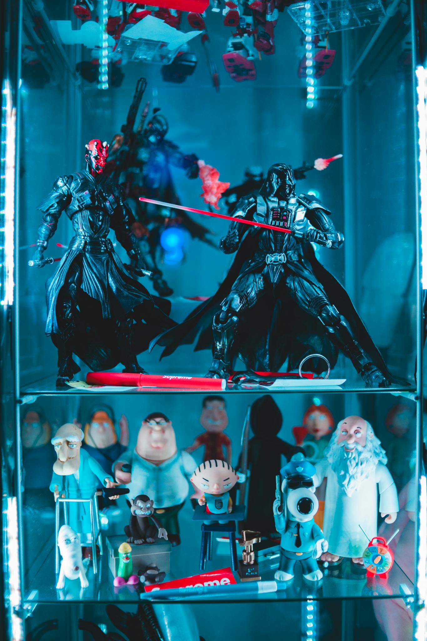 Collection of different assorted figures from movies and cartoons placed in glass shelves with neon light